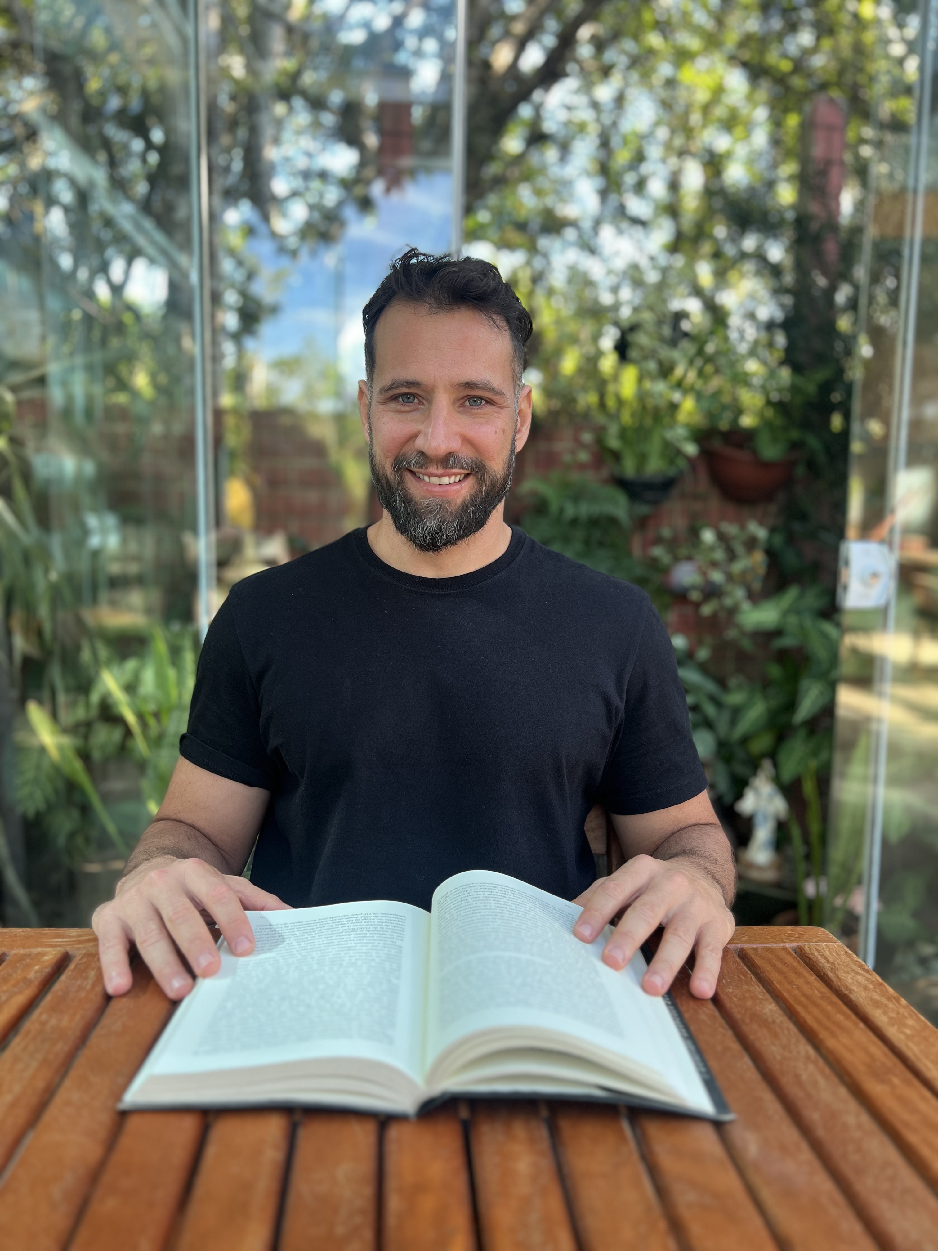 Daniel sentado ao ar livre com o livro de Neurociência aberto sobre a mesa