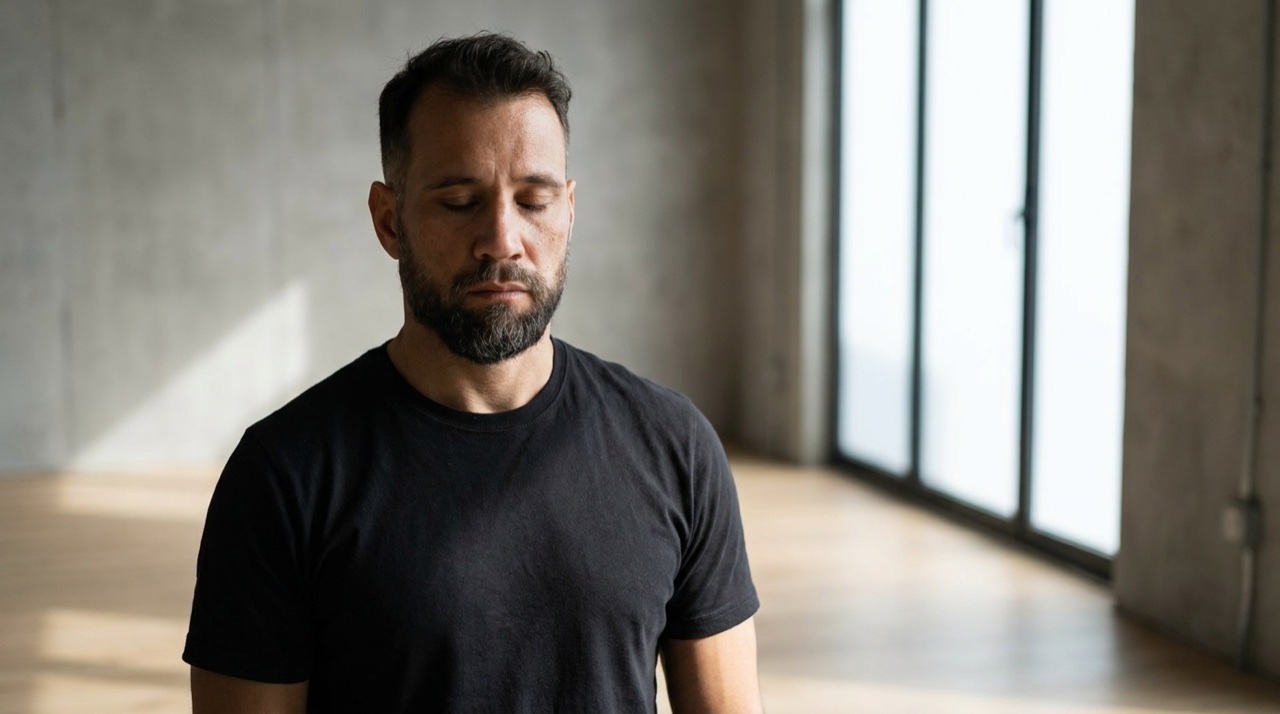 Um homem de olhos fechados, concentrado, preparando-se antes de iniciar uma postura, estudio clean